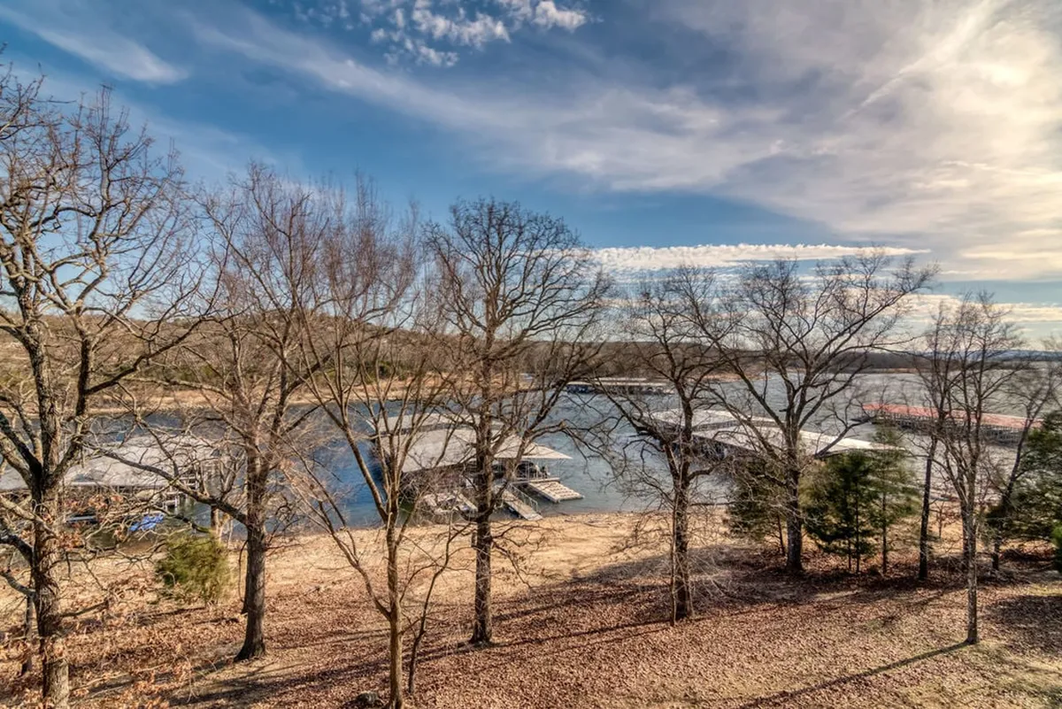 A picturesque view of the lake with boathouses, bare trees, and an open sky. The tranquil water hints at boating, fishing, and lakeshore exploration opportunities, with sunset views enhancing the inviting mood.