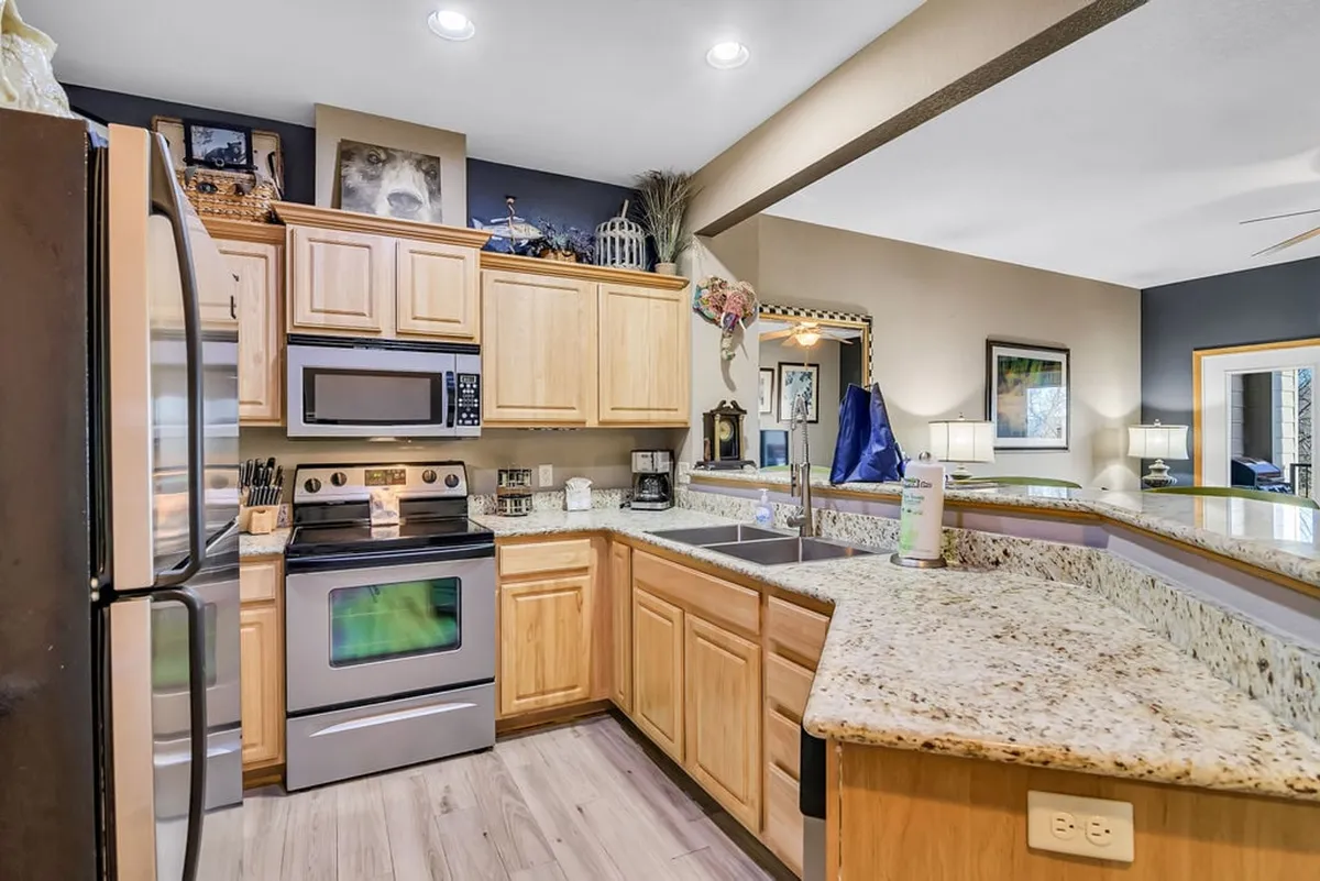 A bright and modern kitchen with granite countertops, stainless steel appliances, wooden cabinetry, and tasteful decorative accents. The space is designed for cooking and entertaining, with plenty of counter space for meal prep and social interaction.