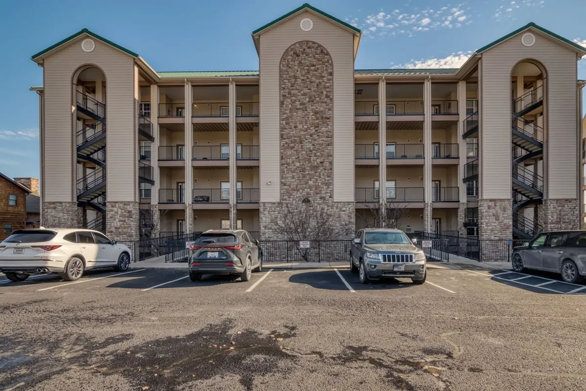 This image highlights the stone facade of the building with welcoming balconies and a staircase, providing a sense of the property's communal outdoor spaces. The scene conveys a mood of family gatherings and outdoor relaxation, tying into the lake experience.